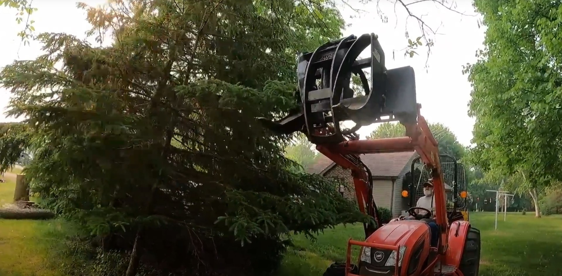 Heavy equipment performing tree removal in residential yard